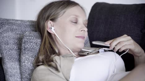 Relaxed-pregnant-woman-listening-to-music-on-sofa